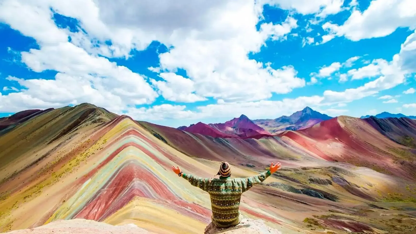 Hiker with arms open at the Rainbow Mountain viewpoint on the Ausangate 2-day trek