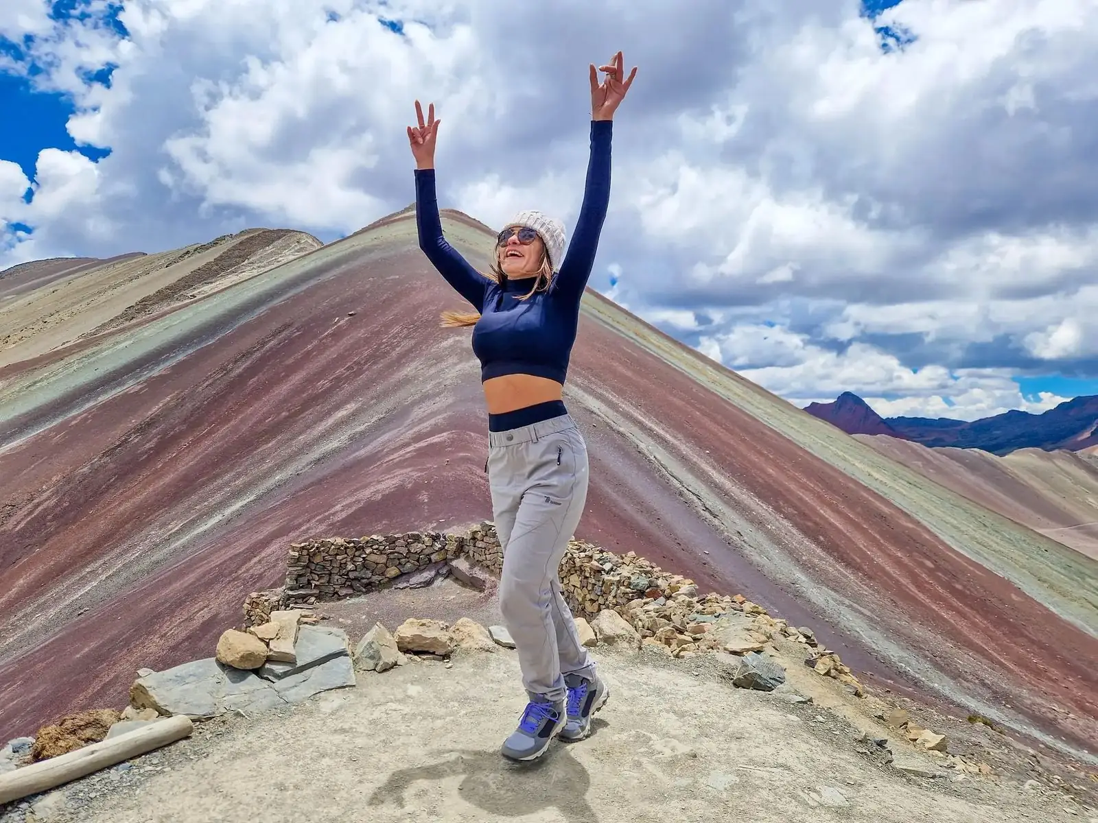 Hiker with arms raised at the summit of Rainbow Mountain on the Ausangate 3-day trek